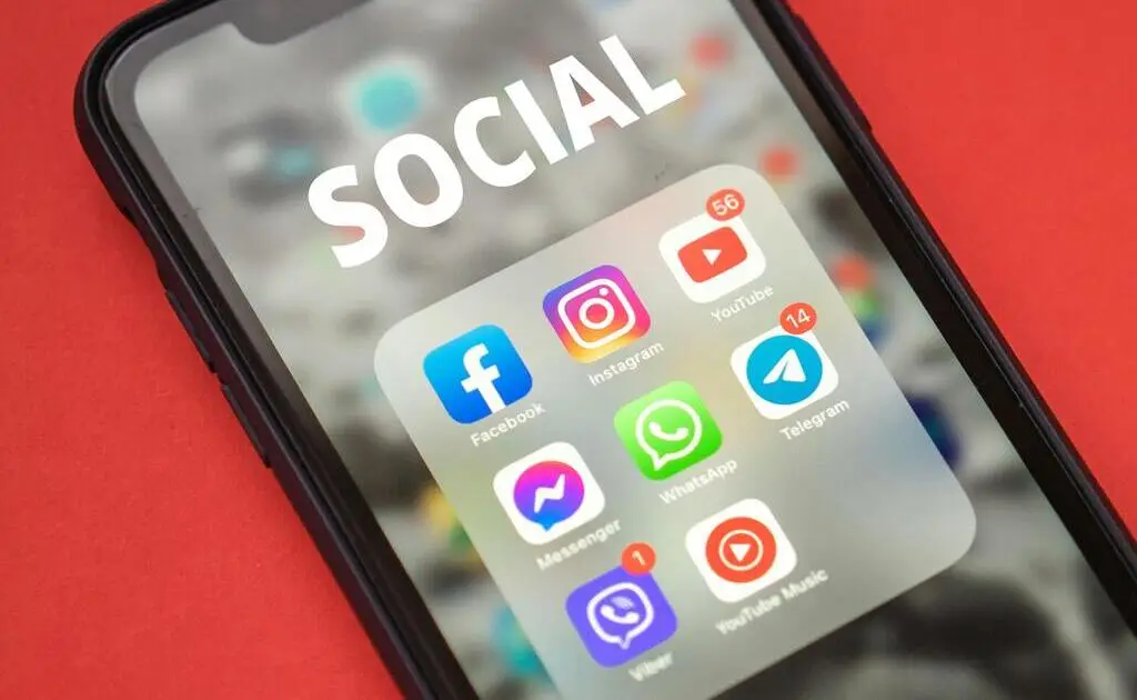 A imagem exibe um smartphone com a tela exibindo diversos aplicativos sociais, tais como Faebook, Instagram, YouTube; e também aplicativos de mensagem instantânea, como Whatsapp, Telegram, Viber; entre outros.